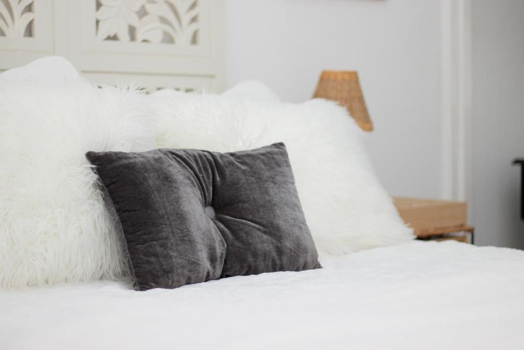 a gray pillow on a white bed with white pillows at 513 on Mulberry in Pretoria