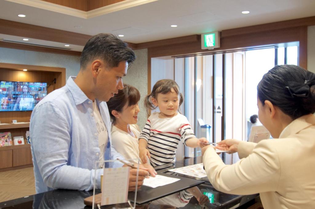 a group of people standing around a table with a child at Hiyori Hotel Maihama in Urayasu