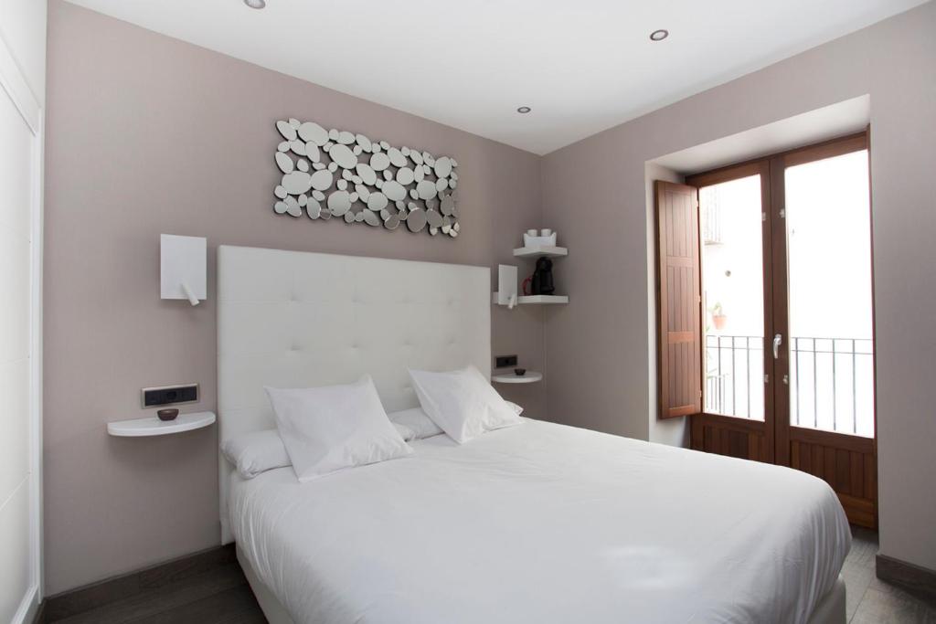 a white bedroom with a white bed and a window at La Sepia Boba (Adults only) in Peñíscola