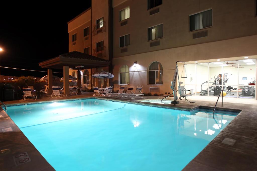 une grande piscine avec éclairage bleu en face d'un bâtiment dans l'établissement Garden Place Suites, à Sierra Vista
