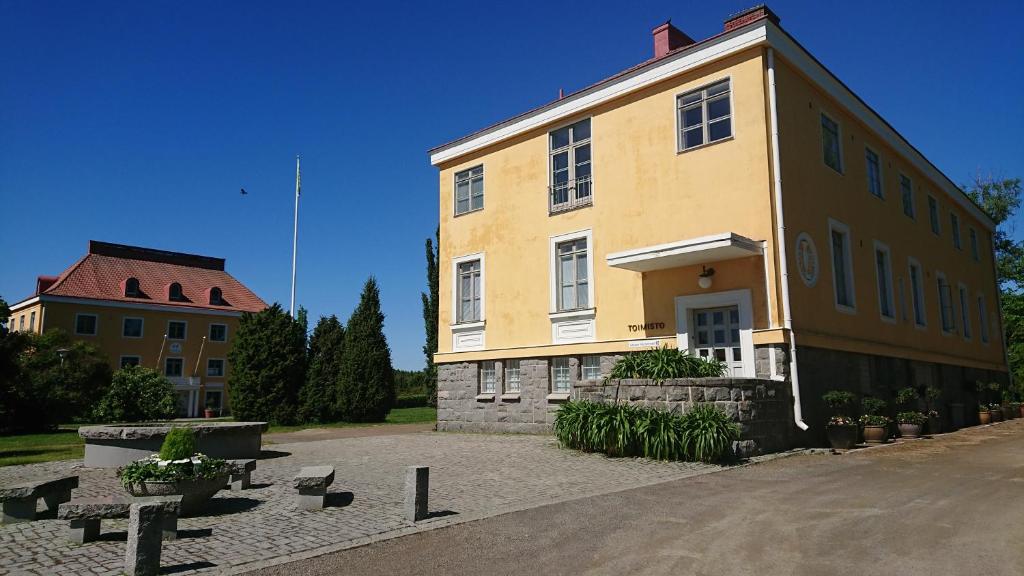 a large yellow building next to a building at Lepaan Kartanon Toimela in Lepaa