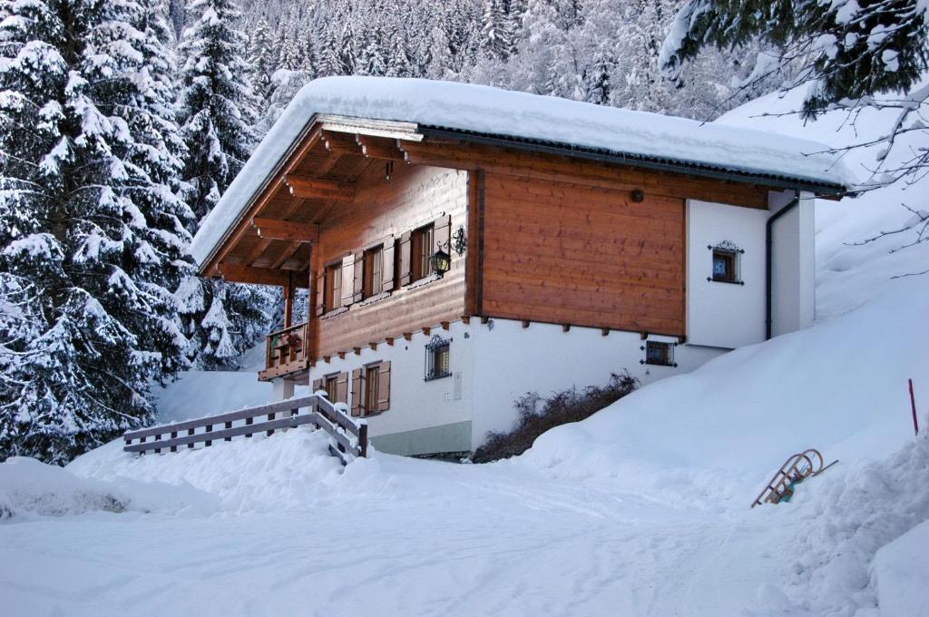 eine Blockhütte im Schnee mit Bäumen in der Unterkunft Alpenstern in Gaschurn