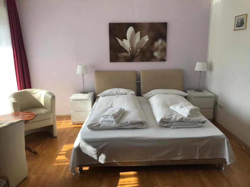 a bedroom with a bed with two pillows and a chair at Hotel-Pension Asta in Munich