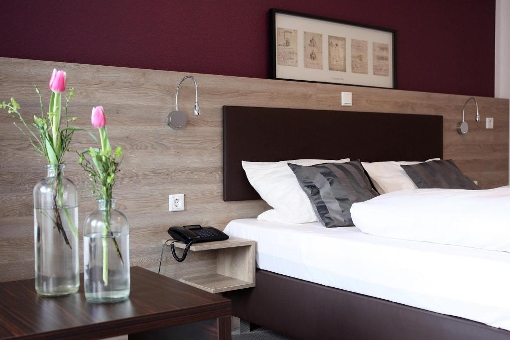 Hotel Kramer في لينهشتات: غرفة نوم مع سرير و مزهرين مع الزهور على طاولة