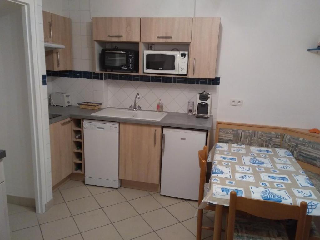 a kitchen with a sink and a table and a microwave at FLAB' MARIN in Le Tréport