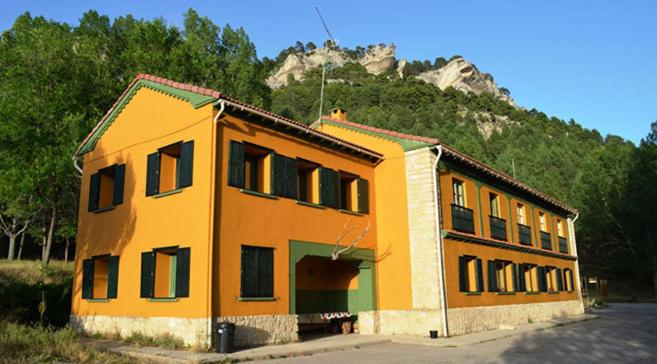 a yellow building with a mountain in the background at Albergue de San Blas in Tragacete