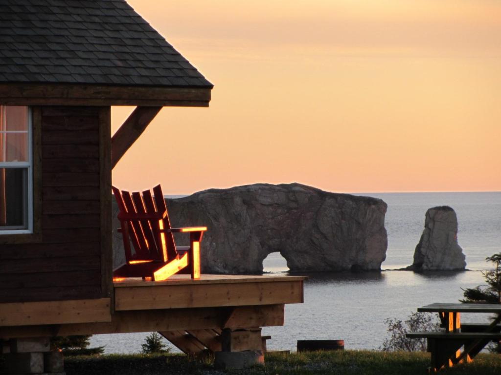 a rocking chair sitting on the porch of a house overlooking the ocean at Chalets Nature Océan in Perce