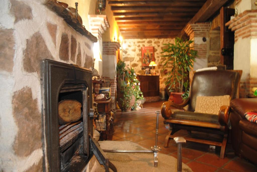 Casa Doña Ligia في Mijares: غرفة معيشة مع موقد حجري مع أريكة وكرسي