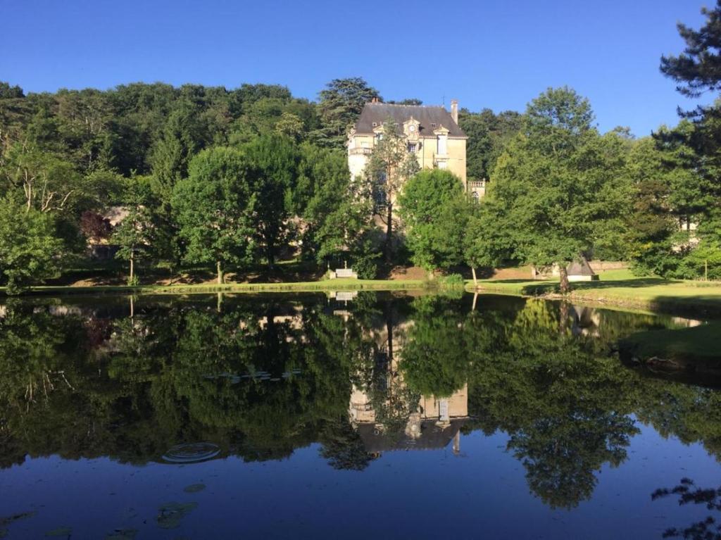 a house is reflected in the water of a lake at Gite Familial Chateau La Roche Racan in Saint-Paterne-Racan