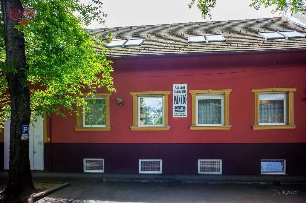 Cívis Szálláshely في ديبريتْسين: مبنى احمر شبابيكه صفراء واشجار