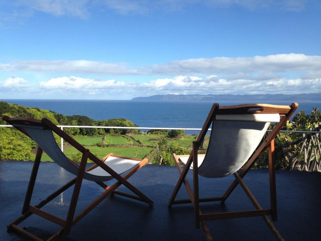 two chairs sitting on a balcony overlooking the ocean at Casa Da Lava in São Roque do Pico