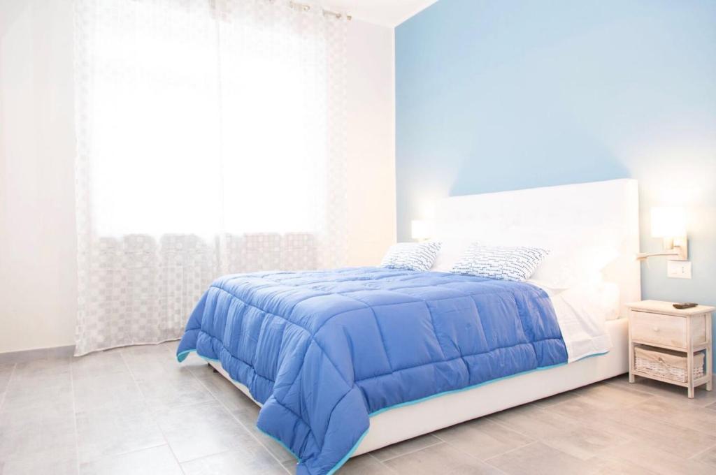 Un dormitorio blanco con una cama azul y una ventana en Gru House, en Grugliasco