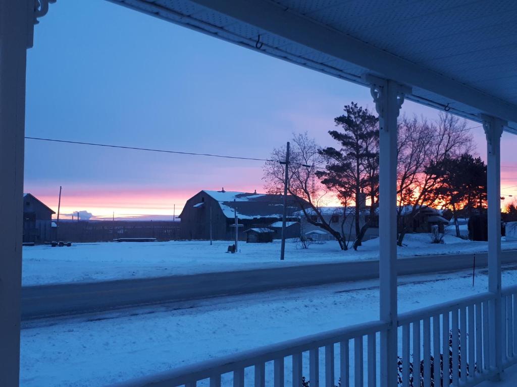 a snow covered yard with a sunset in the background at Les Gites Makadan in Normandin