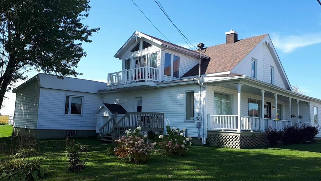 a white house with a balcony on a lawn at Les Gites Makadan in Normandin