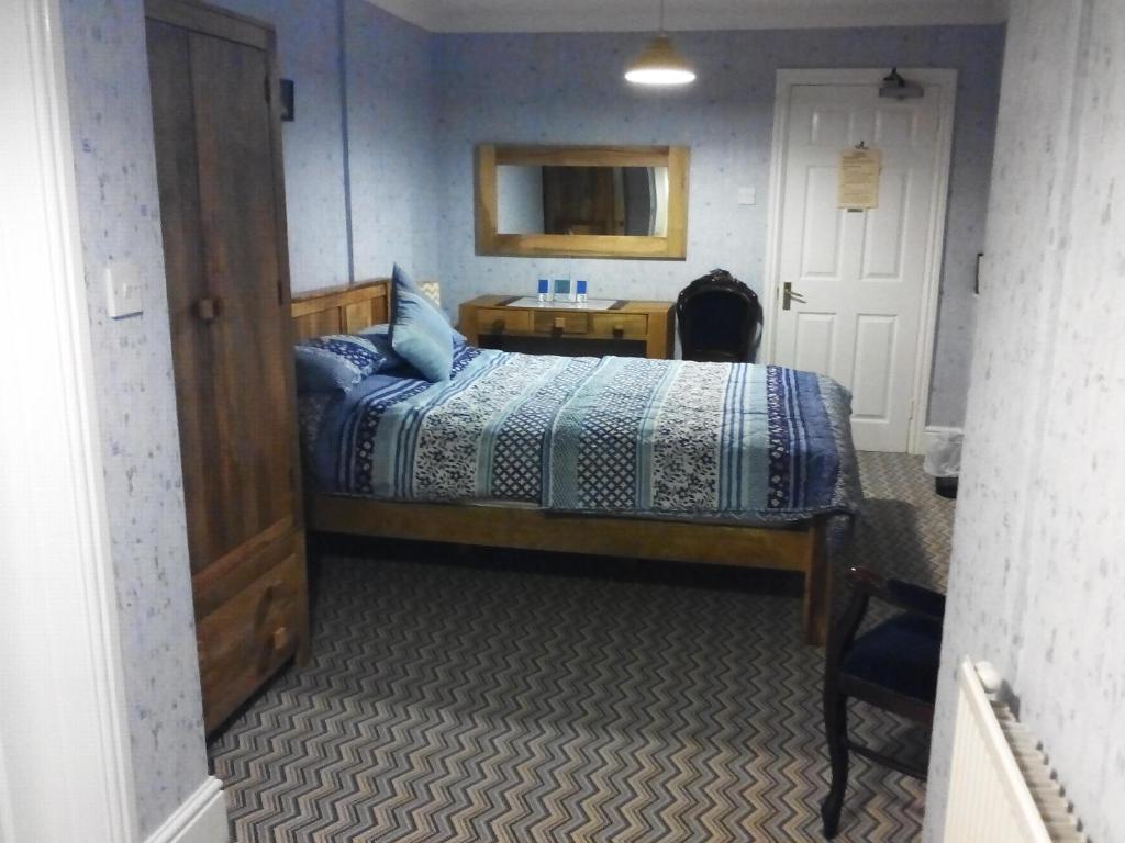a bedroom with a bed with a desk and a mirror at Rosedene Guest House in Pembroke