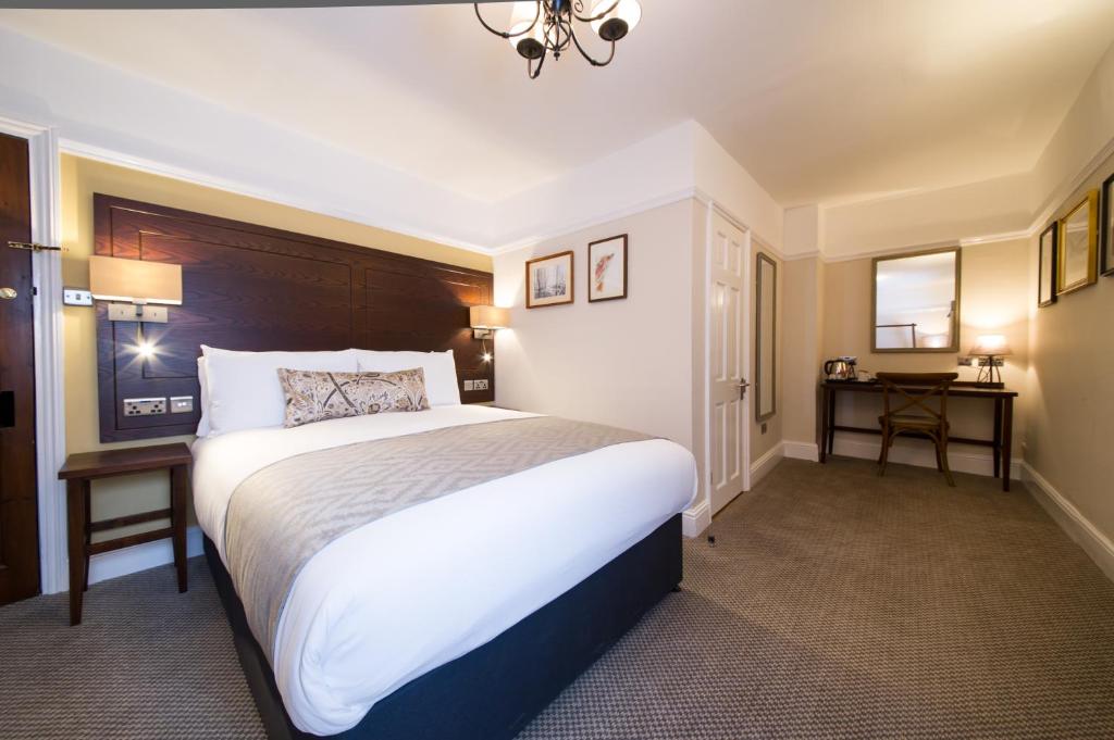 a hotel room with a large bed and two tables at The Colney Fox by Innkeeper's Collection in London Colney