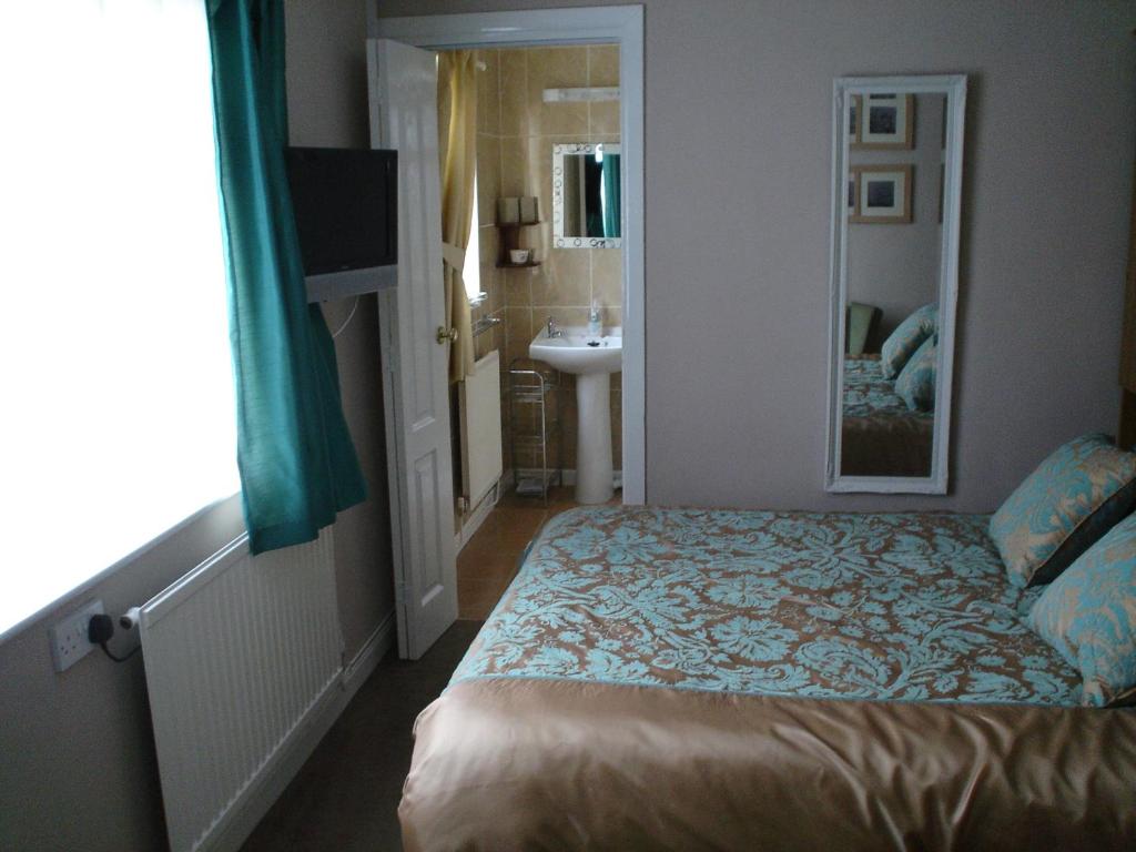 a bedroom with a bed and a bathroom with a sink at Rosedene Guest House in Pembroke