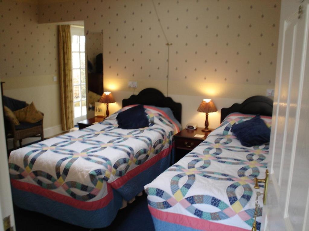 a bedroom with two beds and a chair at Rosedene Guest House in Pembroke