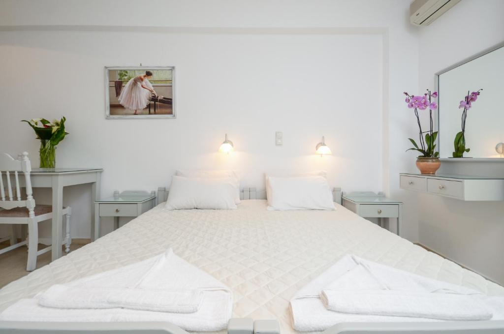 a white bedroom with a large bed with two white chairs at Golden Beach Studios Down Town in Naxos Chora