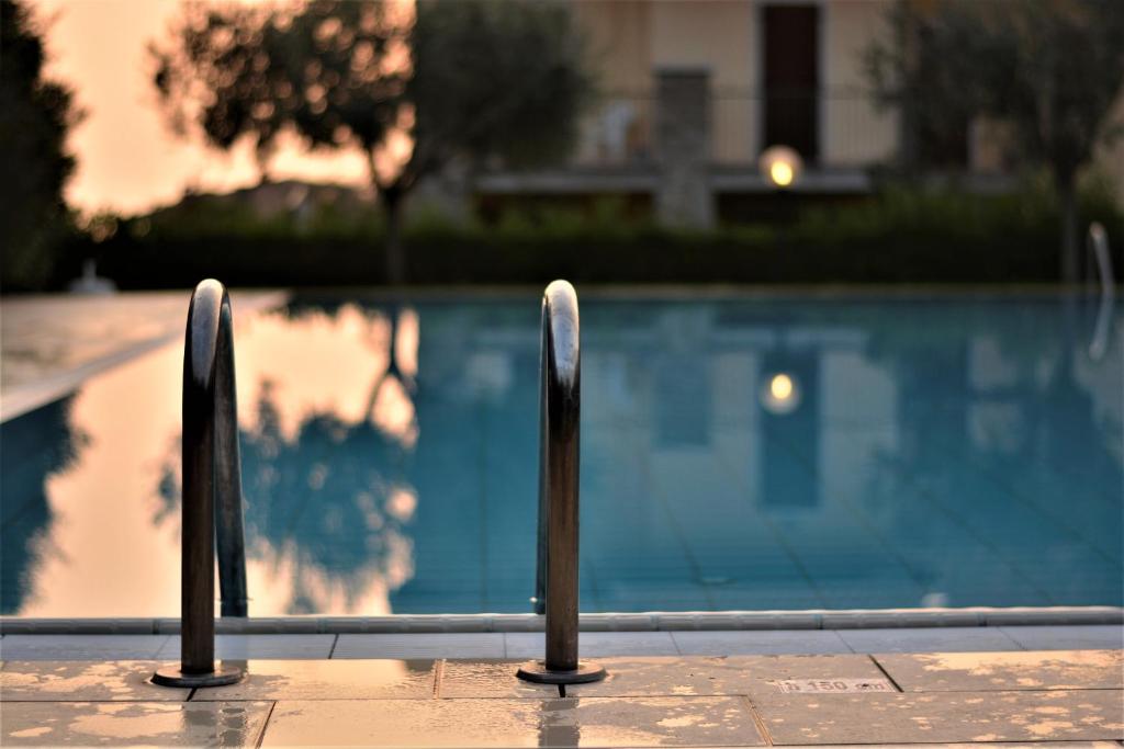 2 pali metallici sono accanto a una piscina di Evelyn POOL apartment -only family- a Bardolino