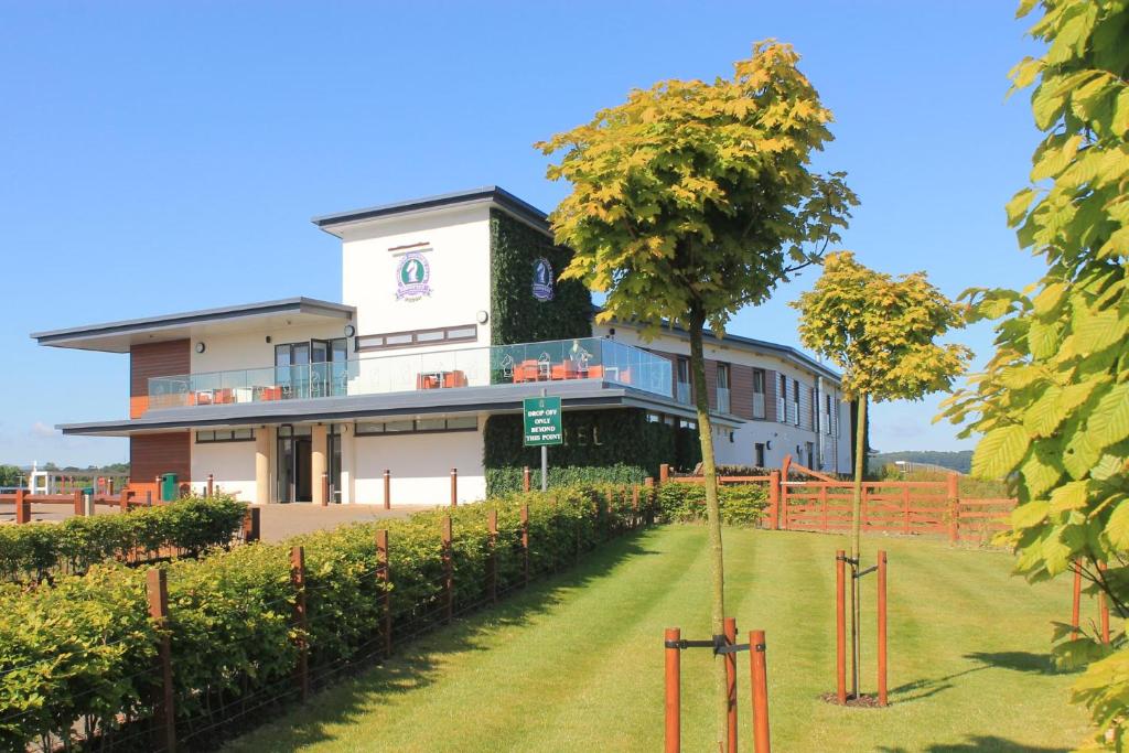 ein großes weißes Gebäude mit einem Baum davor in der Unterkunft Ingliston Country Club Hotel in Bishopton