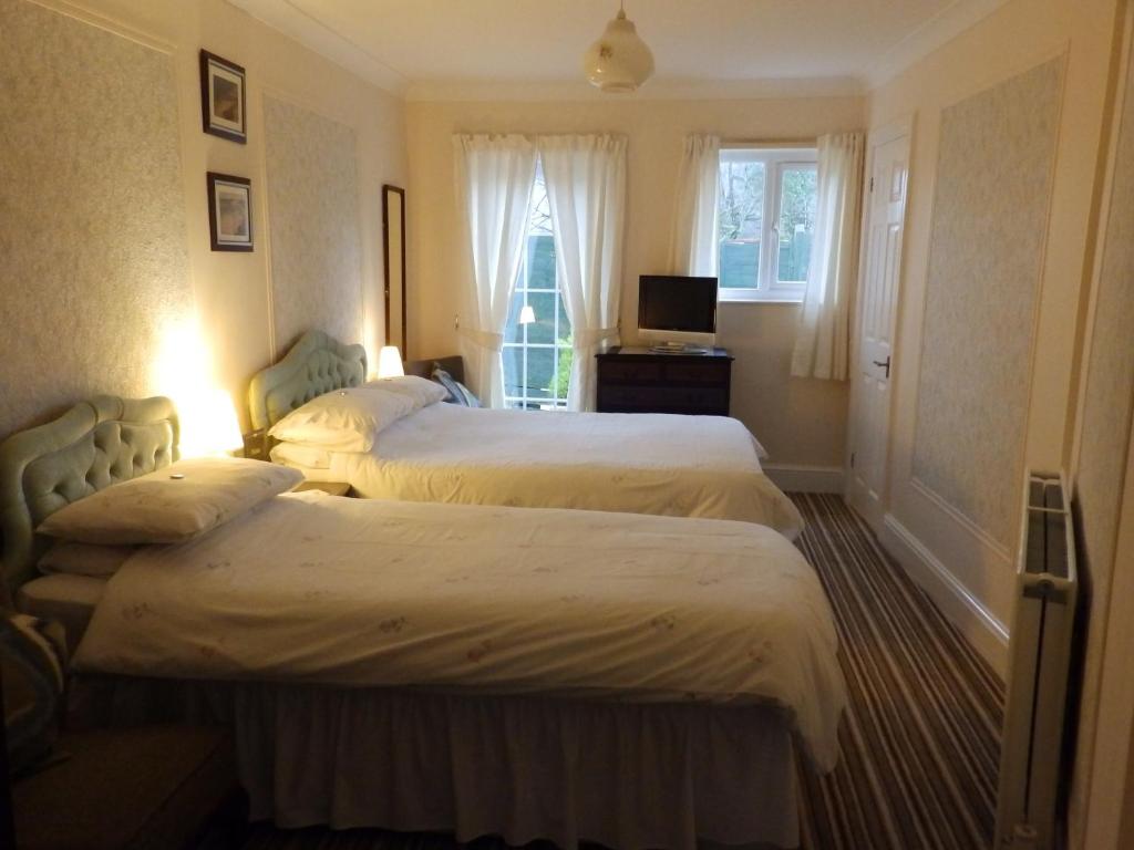 a hotel room with two beds and a television at Rosedene Guest House in Pembroke