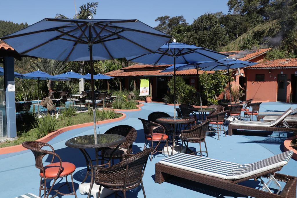 un patio al aire libre con mesas, sillas y sombrillas en Hotel Rural Vale das Nascentes en Salesópolis
