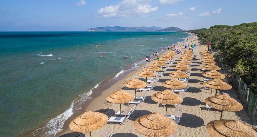 una spiaggia con ombrelloni e persone sull'acqua di Camping Village Oasi ad Albinia