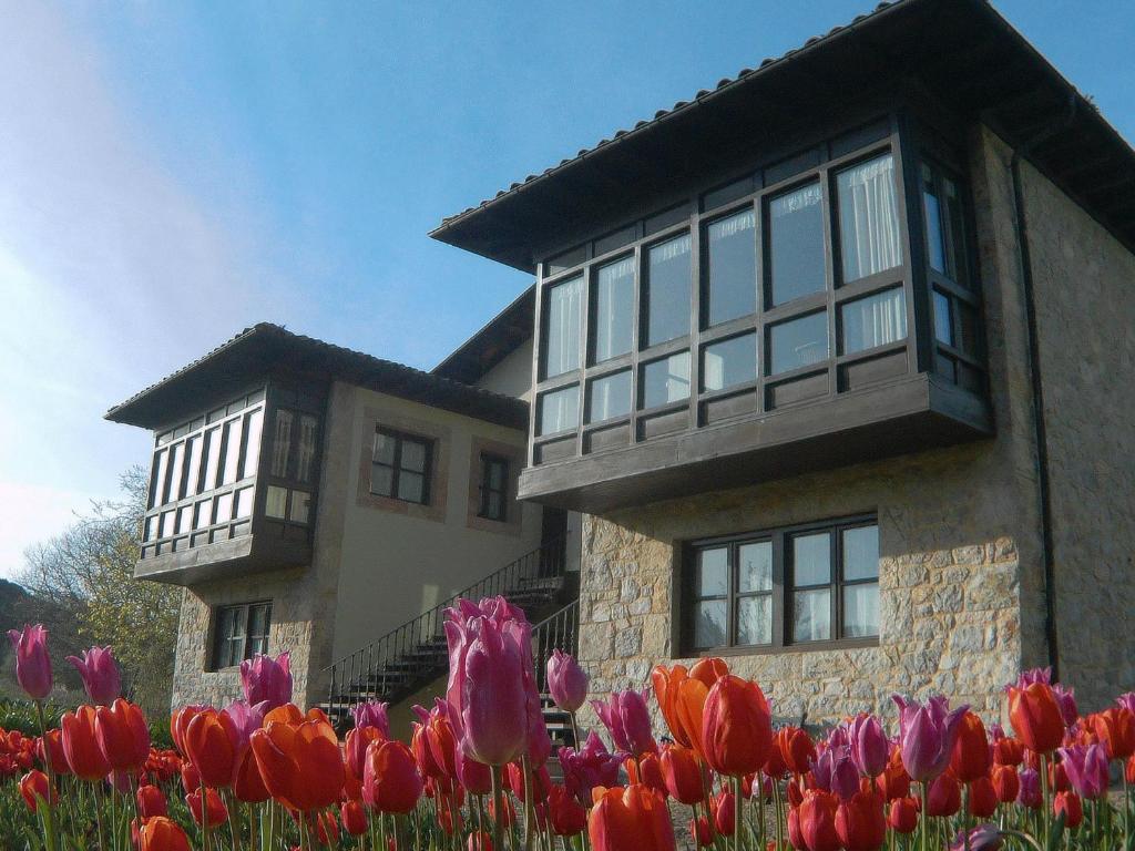 una casa con tulipani colorati davanti di Apartamentos Turísticos Las Nieves a Poo de Llanes