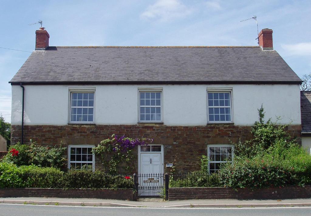 a white and red brick house with a white door at Claw House in Holsworthy