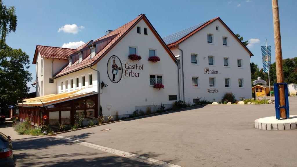 un grand bâtiment blanc dans un parking dans l'établissement Hotel - Gasthof Erber, à Sinzing