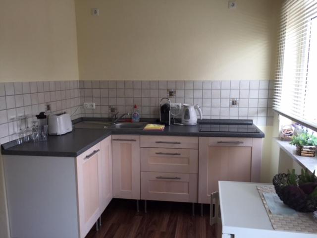 une cuisine avec des armoires blanches et des comptoirs noirs dans l'établissement FeWo und Zimmer Egert, à Hattenheim