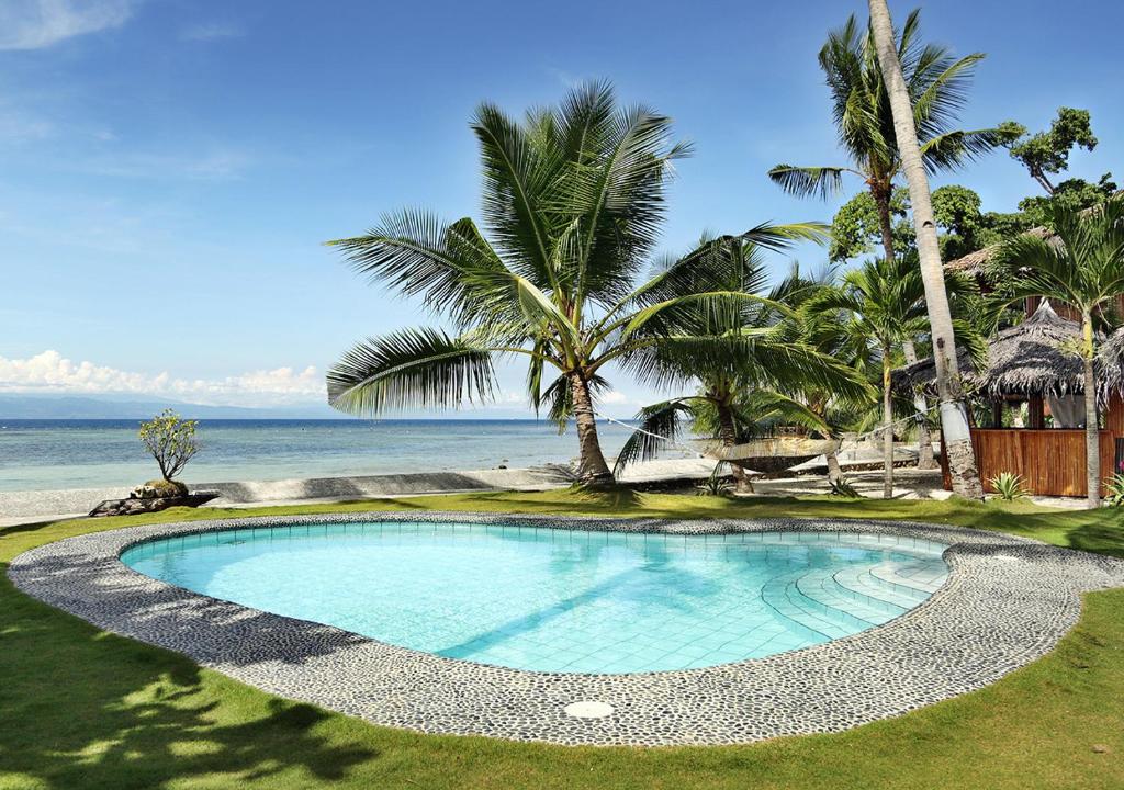 una piscina junto al océano con palmeras en Les Maisons D'Itac, en Ronda