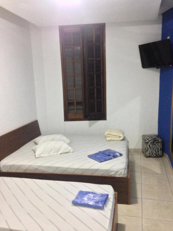 a room with two beds and a window and a tv at Hotel Florêncio in Sao Paulo