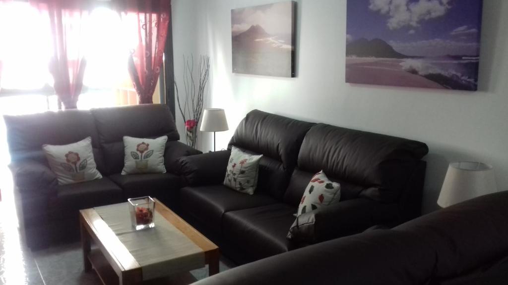 a living room with a leather couch and a coffee table at Neptuno Rooms in Arrecife