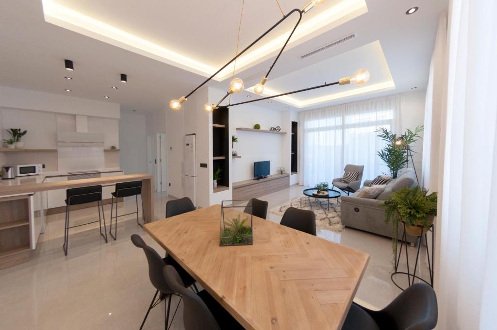 cocina y sala de estar con mesa de madera y sillas en Apartamentos La Laguna I Luxury Apartments, en Guardamar del Segura