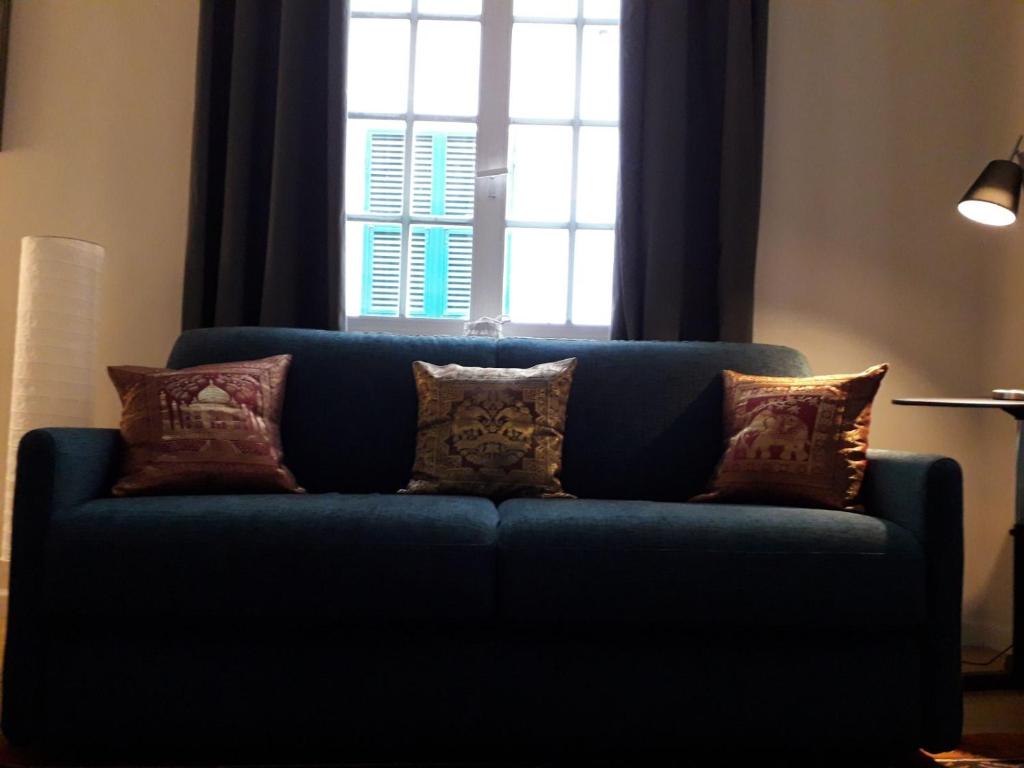 a blue couch with pillows in front of a window at Cosy Little House in Genova