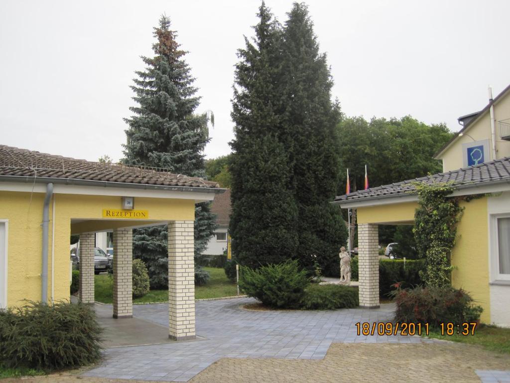 ein gelbes Gebäude mit einem Tor in einer Einfahrt in der Unterkunft Hotel Merkur Garni in Sarstedt