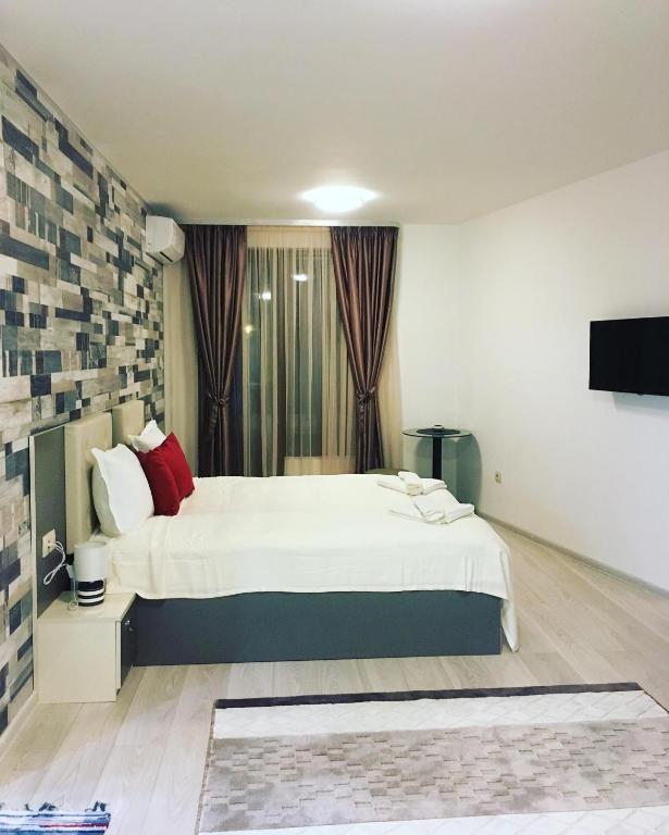 a bedroom with a large white bed with red pillows at Apartments Park Place in Sandanski