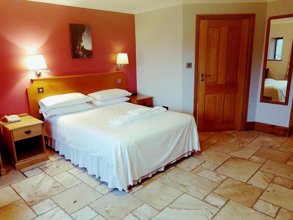 a bedroom with a large bed with white sheets at King's Head Inn in Llangennith