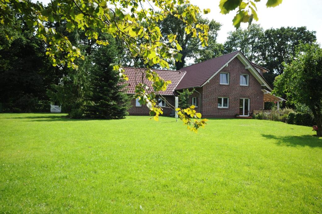 ein Haus mit grünem Rasen davor in der Unterkunft Mergelhof in Rhauderfehn