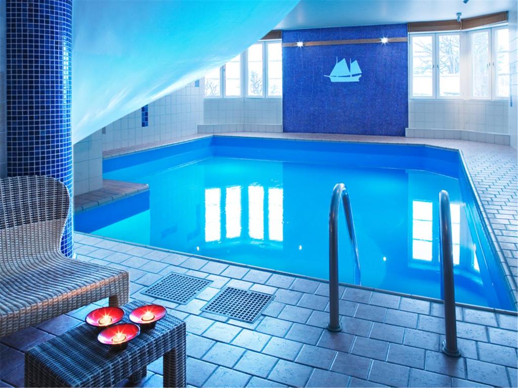 a blue swimming pool with a table and a chair at Quality Hotel Statt in Hudiksvall