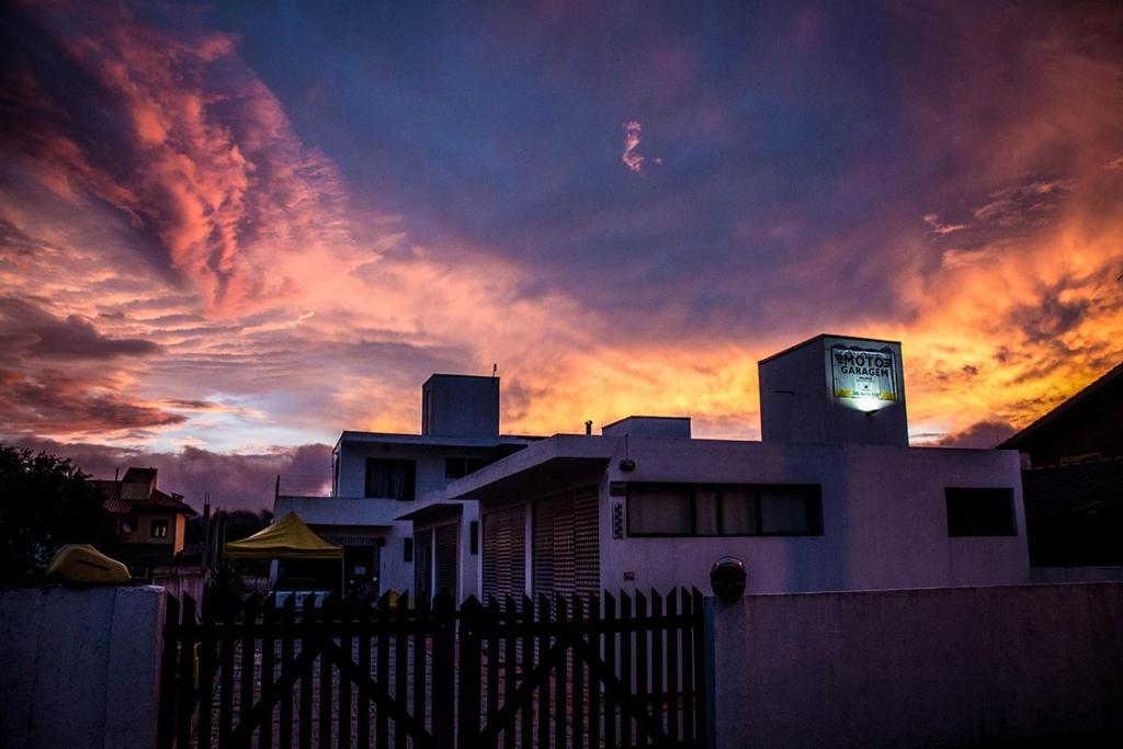 une maison avec un coucher de soleil en arrière-plan dans l'établissement MotoGaragem, à Urubici