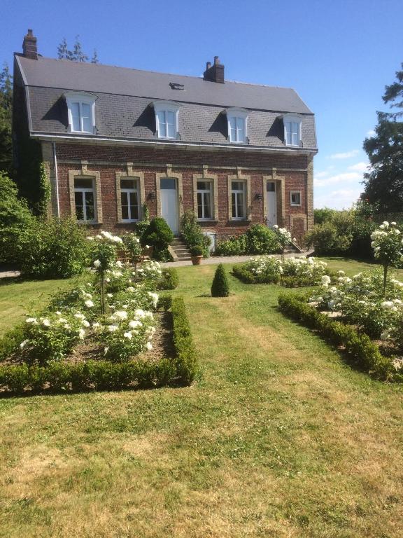 une grande maison en briques avec des fleurs blanches dans la cour dans l'établissement Le Clos Boutenelle, à Éperlecques