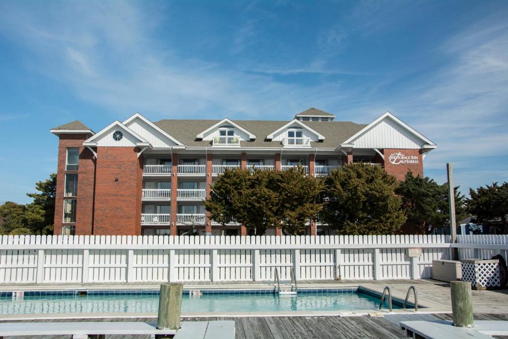 a building with a white fence in front of a pool at Anchorage Inn & Marina in Ocracoke