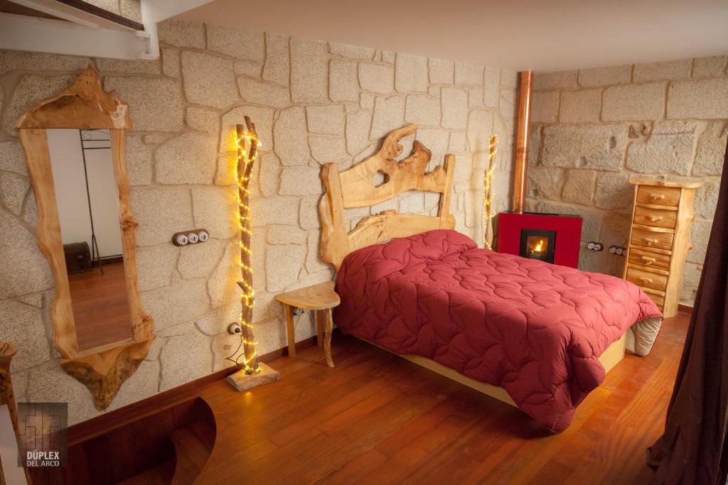 1 dormitorio con 1 cama en una pared de piedra en Dúplex del Arco, en Cangas de Morrazo
