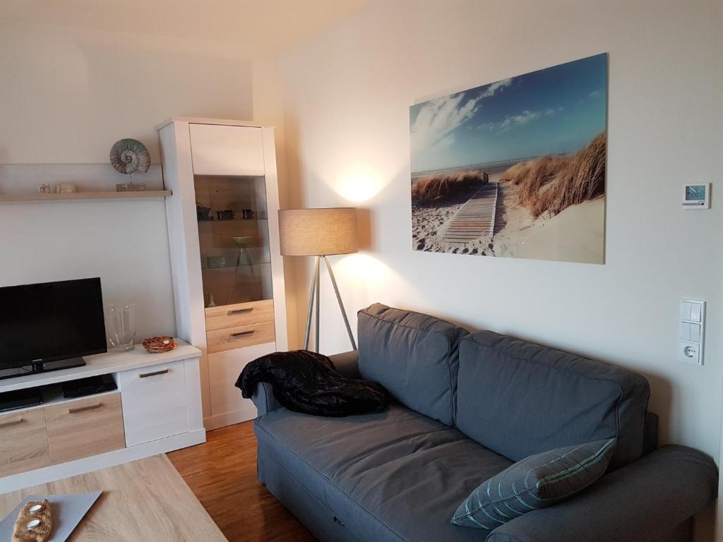 een woonkamer met een bank en een flatscreen-tv bij Ferienwohnung Caprinus in Büsum