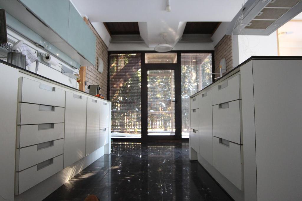 a kitchen with white cabinets and a large window at Champêtre Park View Apartments in Riga