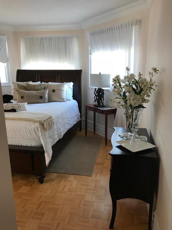 1 dormitorio con 1 cama y un jarrón de flores sobre una mesa en Molly's Retreat B and B, en Orangeville