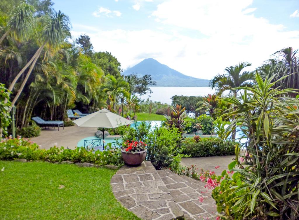 a garden with a patio and a view of the water at Hotel San Buenaventura de Atitlán in Panajachel